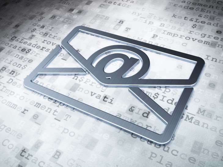 Ein silberner Briefumschlag mit dem E-Mail-@-Zeichen liegt auf einem Dokument